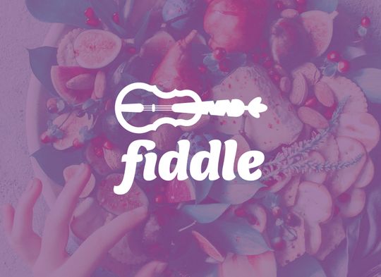 Fiddle logo placed on a hipster bowl of fruit with a hand reaching in for a dark red cherry